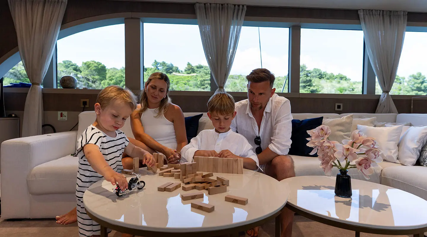 Group of five people dining on a yacht deck with tables and drinks aboard Nocturno