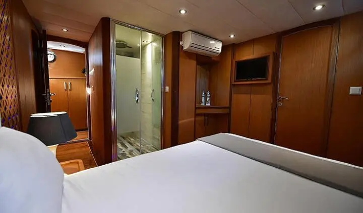 Master cabin with king bed, dark wood cabinetry, ensuite bathroom visible