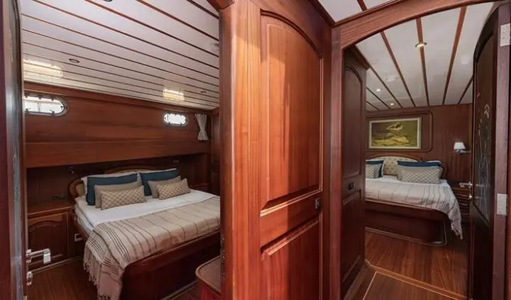 Yacht master cabin with king bed, wooden cabinetry, ensuite door frame