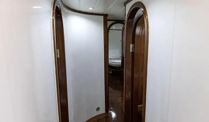 Small cabin hallway on yacht with wooden doors and curved walls