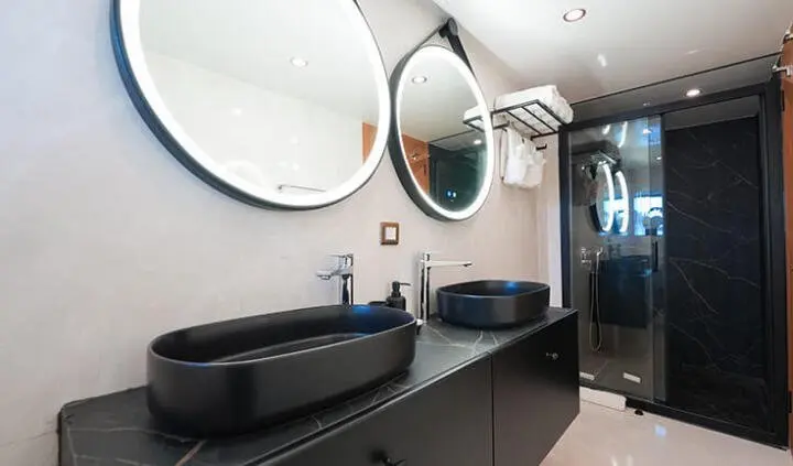 King of the Sea master cabin with dark wood vanity, round mirror, and bed