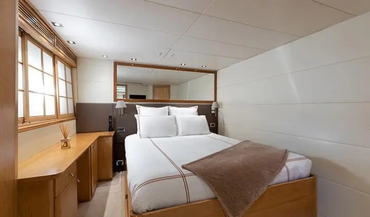 Luxurious yacht cabin with king bed, white bedding, and overhead cabinets