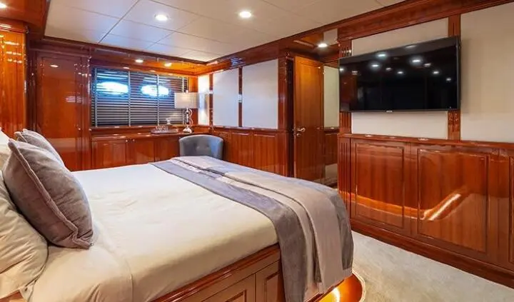 Master cabin with king bed, wooden paneling, ensuite visible, warm lighting