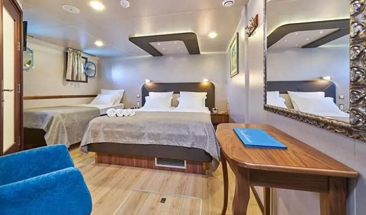 Casablanca cabin with a large bed, wooden floor, seating, and compact bathroom area visible