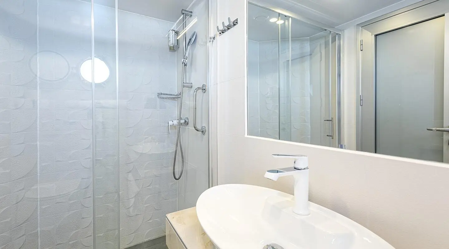 Yacht bathroom detail on Yolo: glass shower, tiled walls, white sink