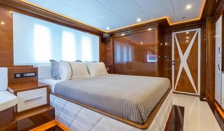 A king bed in a cabin with wood paneling and windows on left