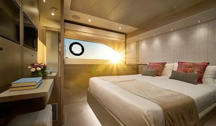 Twin beds in a yacht cabin with wood finishes and a small window