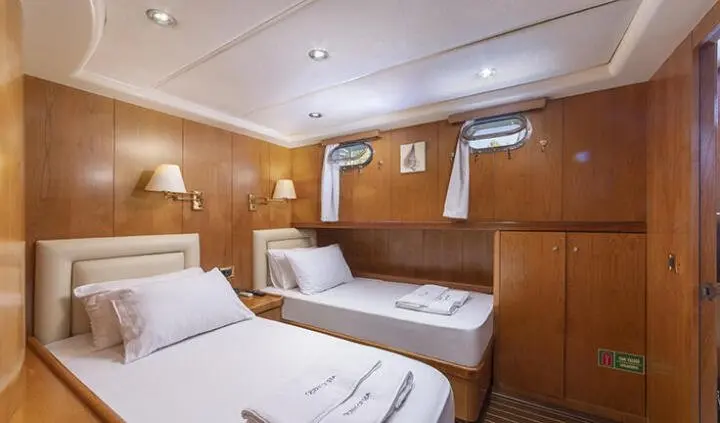 Twin cabin aboard Queen Of Sea yacht with two single beds and wooden paneling