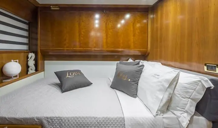Amoraki yacht cabin with double bed, wood cabinetry, and pillows