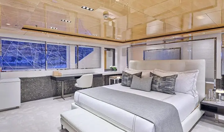 Luxurious yacht master cabin with large bed, porthole windows, and wooden overhead panels