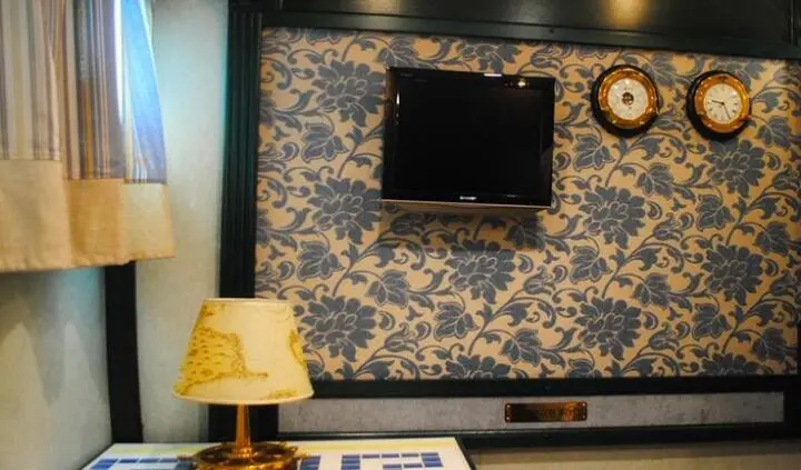 Master cabin with king bed, patterned wallpaper, and wall mounted TV