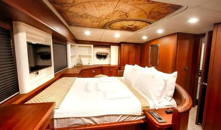 Master cabin with king bed, white linens, wooden cabinets, ensuite area