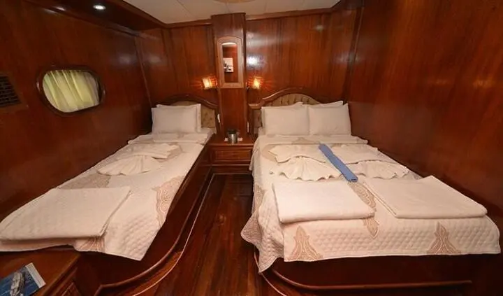 Double cabin on a wooden yacht interior with two single beds and bedside table