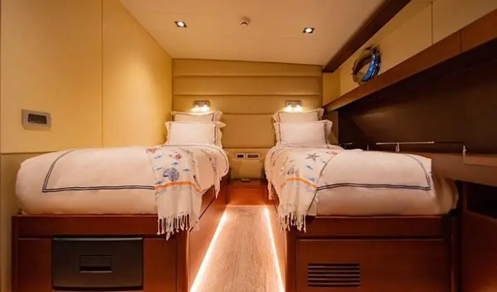 Twin beds in a warm cabin with stacked linens and wooden surroundings