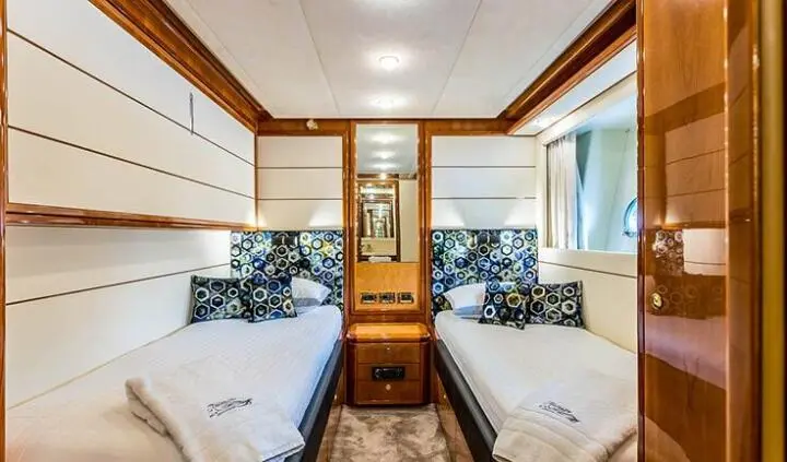 Twin cabin with two single beds, shared ensuite, wooden cabinetry, porthole window