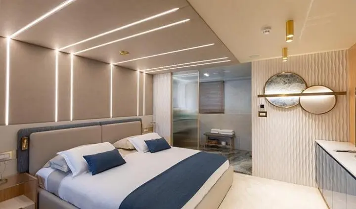 Master cabin with king bed, white and navy decor, ensuite door visible
