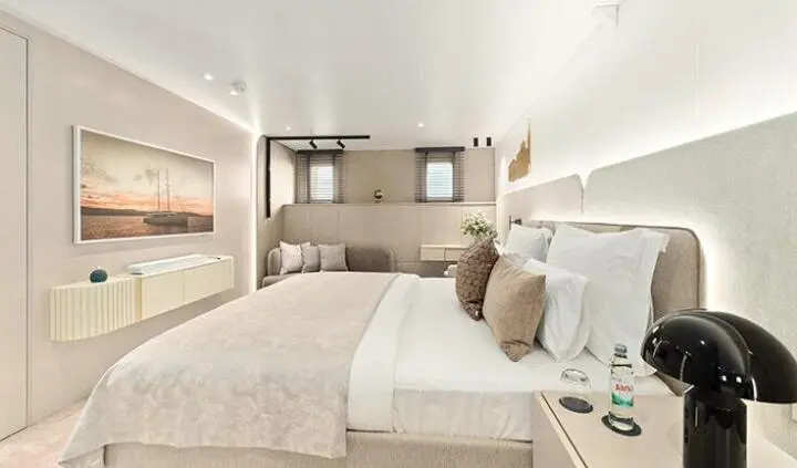 Master cabin with king bed, beige linens, ensuite bath, windows, decorative pillows