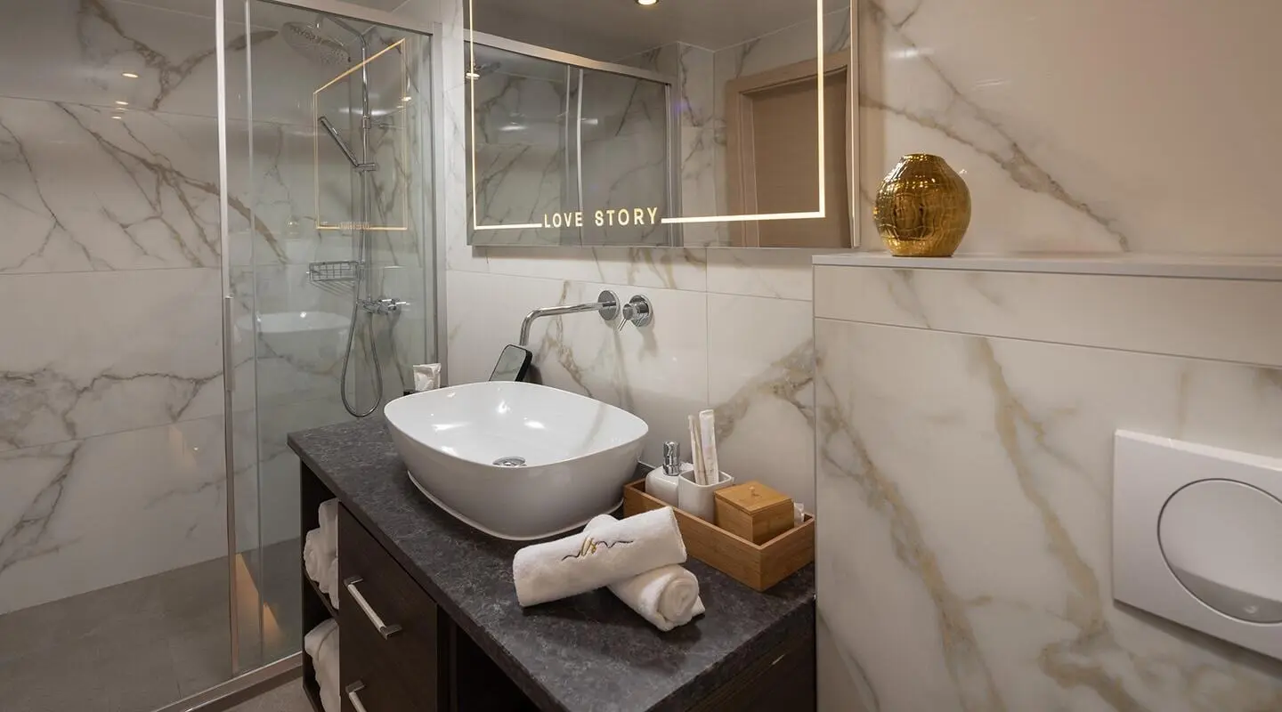 Onboard bathroom with marble shower walls and a modern sink on a yacht