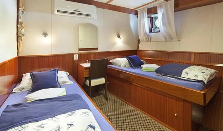 Interior of Tajna Mora twin cabin with two blue beds and wooden storage