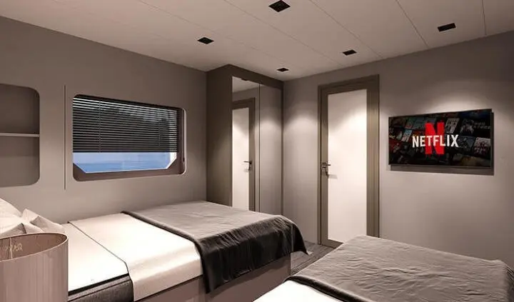 Two twin beds in a cabin with a view window and neutral decor aboard a yacht