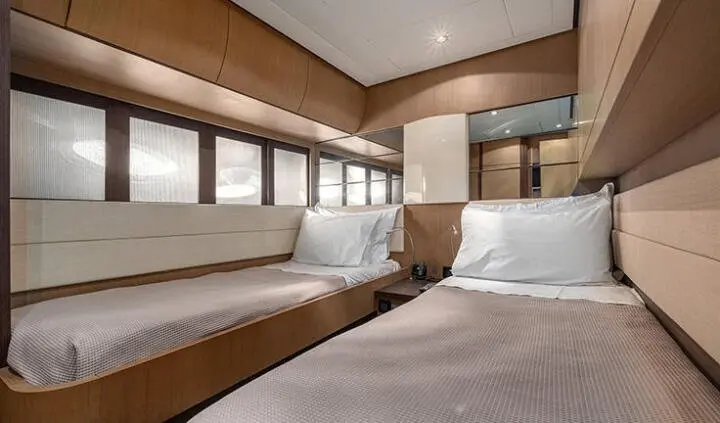 Interior of yacht cabin with wooden paneling, two beds and white pillows