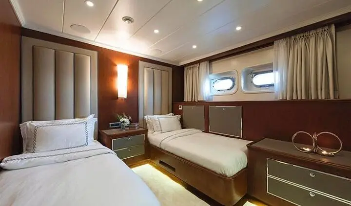 Twin cabin on Ocean Breeze yacht with two beds, wood panels, windowed wall
