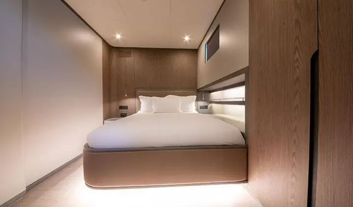 Master cabin with king bed, white bedding, wood-paneled walls, ensuite door