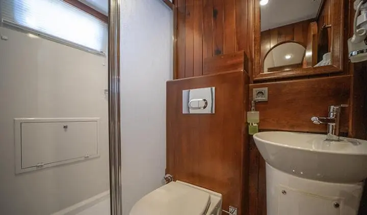 Guest cabin ensuite bath on Ulucinar yacht, wooden walls and compact shower