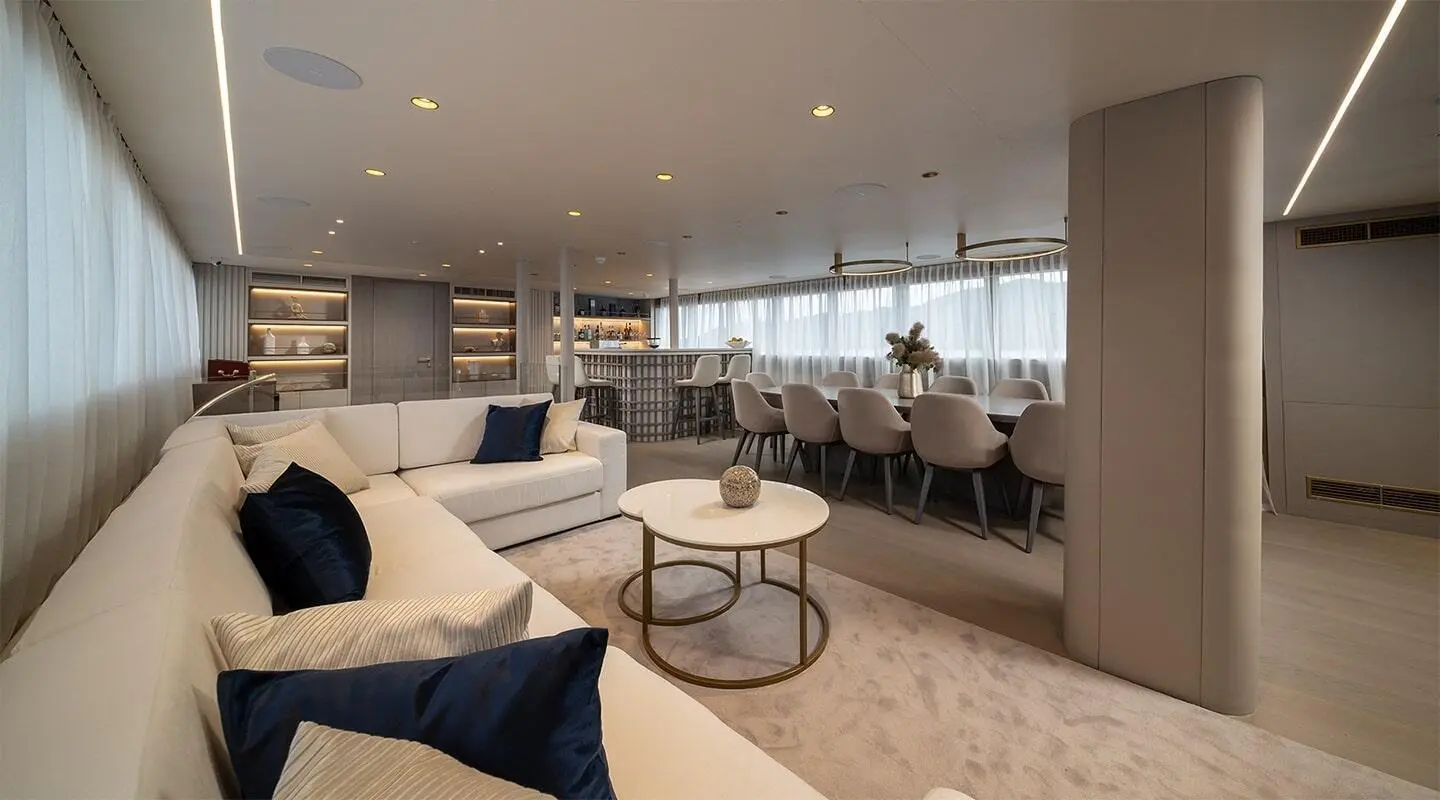 Nocturno yacht salon at sunset with seating, tables, and soft lighting