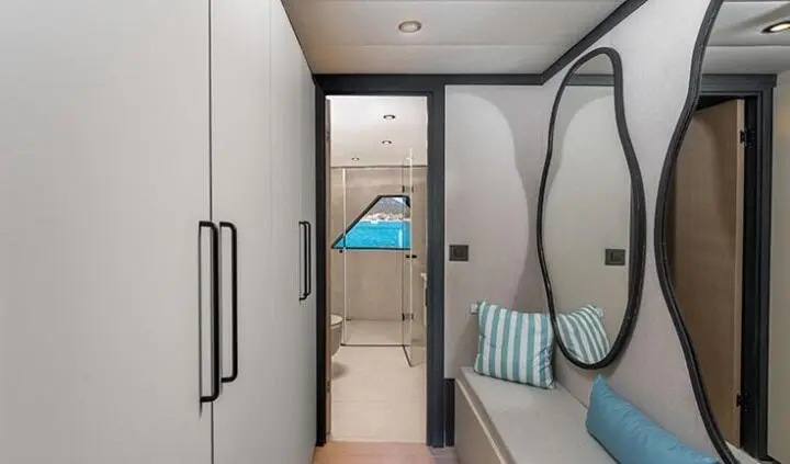 Luxurious yacht cabin with king bed and ensuite door, view to corridor