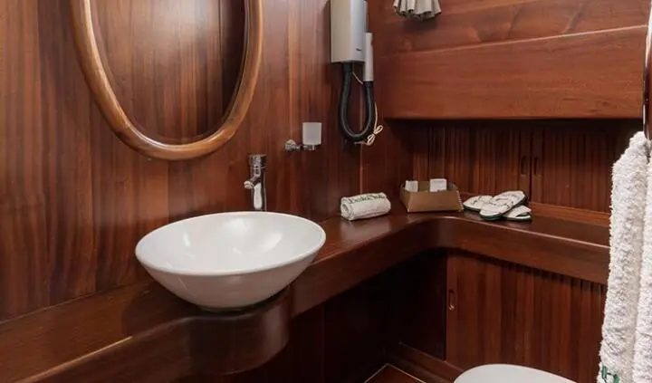 Yacht cabin ensuite with white oval sink and wooden cabinetry
