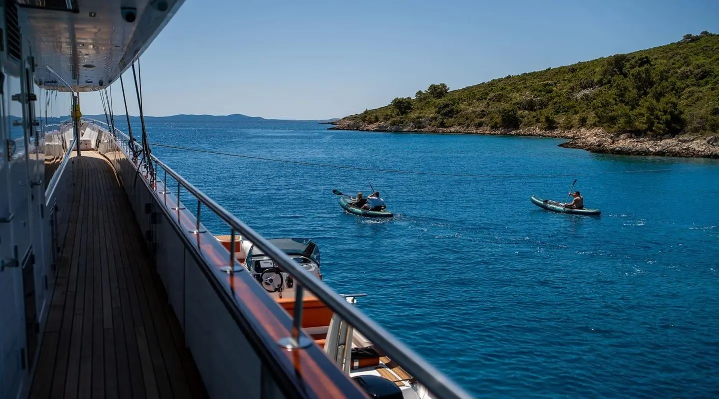 Anima Maris yacht viewed from the deck with blue water and a small boat nearby