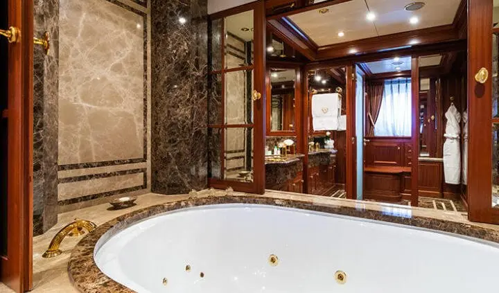 Inside cabin of Apogee yacht with luxurious wooden decor and spa tub visible
