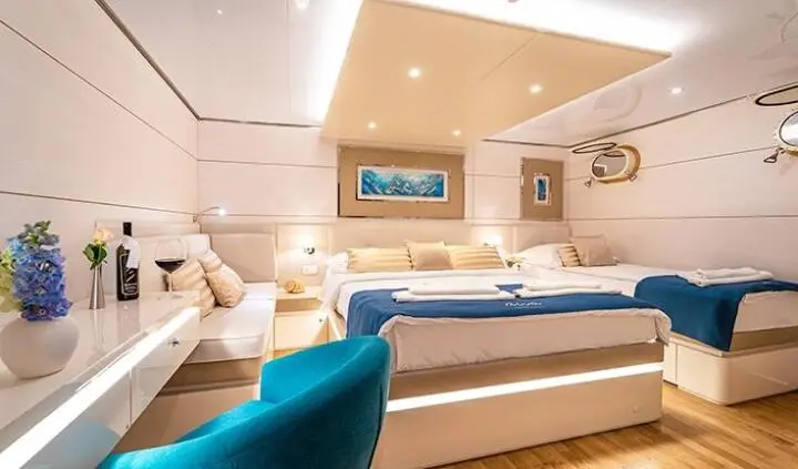 Master cabin with king bed, ensuite, soft lighting, and seating area on yacht