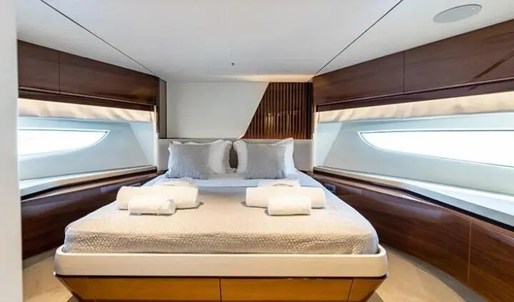 Vista yacht cabin with king bed, white bedding, wooden bedside cabinets, and windows