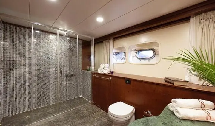 Ocean Breeze master cabin with king bed, ensuite, wooden walls, porthole window, and tile floor
