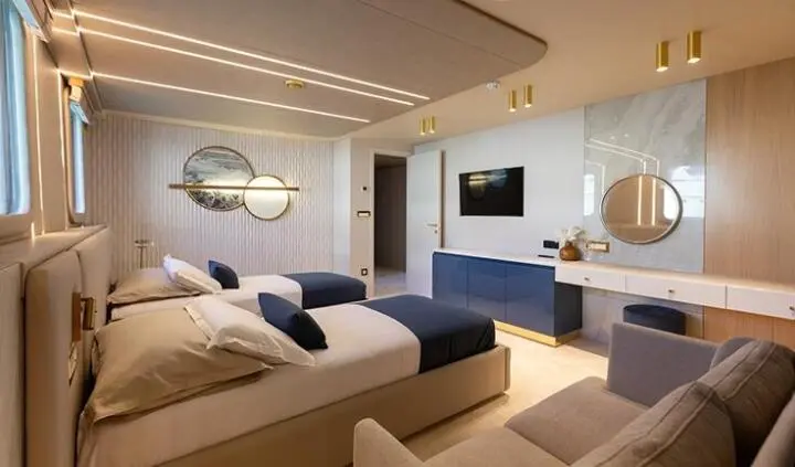 Scorpios cabin interior with twin beds, seating area, and nautical decor