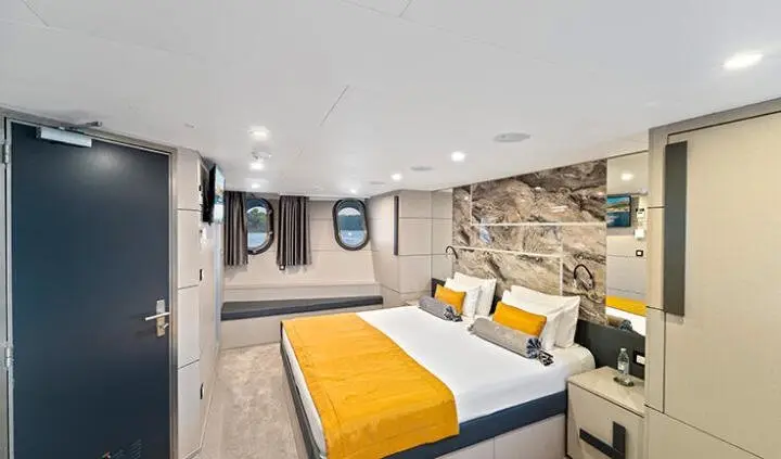 Master cabin with king bed, yellow throws, ensuite bathroom, stone wall accents