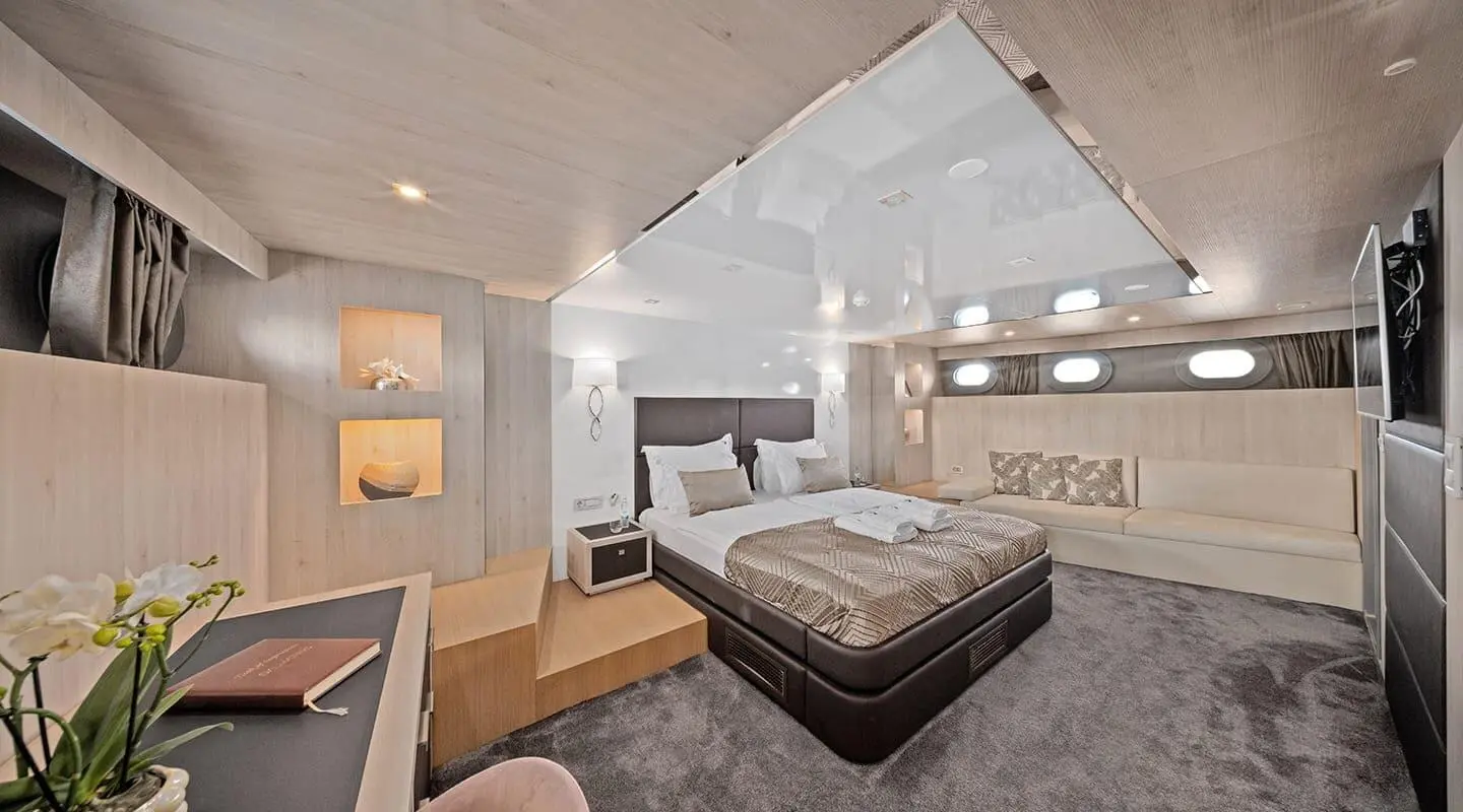 Dalmatino yacht suite interior with large bed, neutral tones, warm lighting