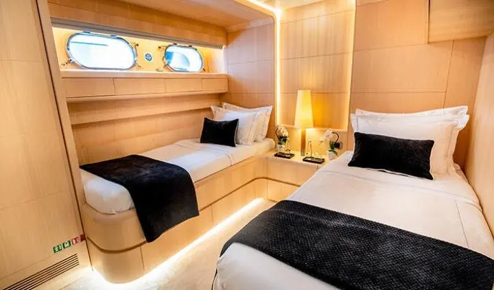 Pareaki II cabin with two single beds, wood paneling, porthole windows, bedside lamp