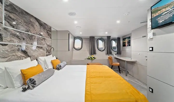 Luxurious yacht cabin with a king bed, yellow runner, and seating area