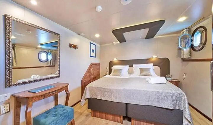 Casablanca cabin with king bed, white bedding, bedside lamps, seating area