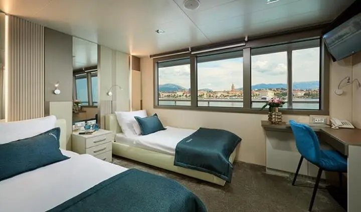 Interior cabin of Ohana yacht with twin beds, seating, and large window view