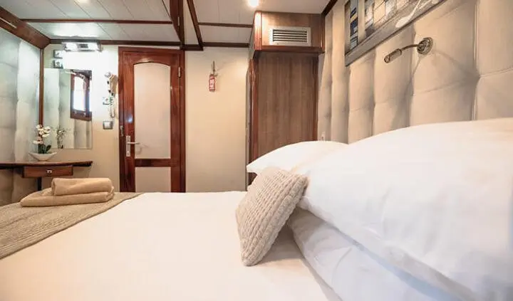 Mendula yacht cabin with double bed, pillows, wood panels and ensuite door