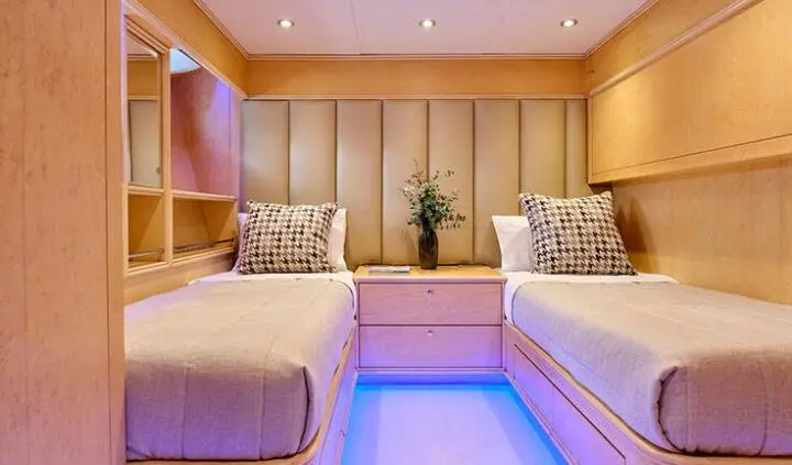 Twin cabin with berth aboard Mobius yacht, warm wooden interior and built-in lighting