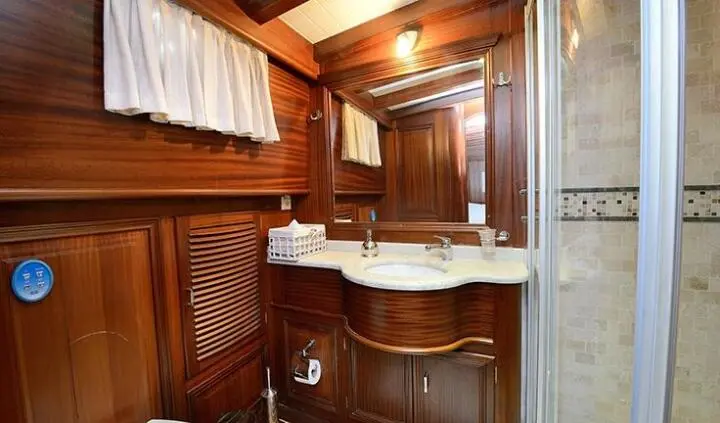 Cozy yacht cabin with wooden cabinets, wardrobe, and curved sink area