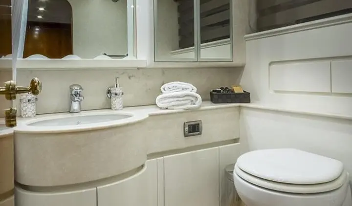 Master cabin with king bed, ensuite area, beige cabinetry and fixtures
