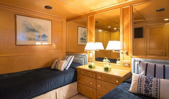 Twin cabin with two single beds separated by a nightstand and wooden cabinetry