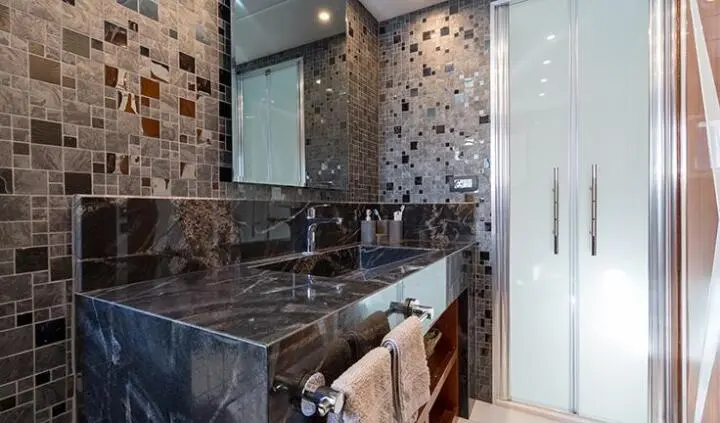 Luxurious yacht cabin with dark wood vanity, large mirror, and patterned tile walls