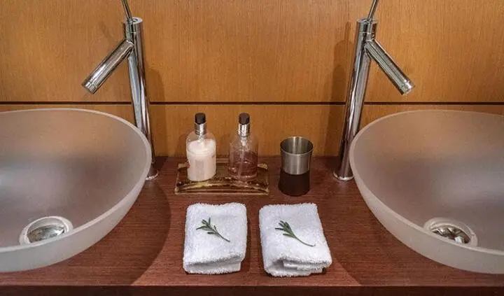 Two sinks with chrome faucets and folded towels on wooden counter